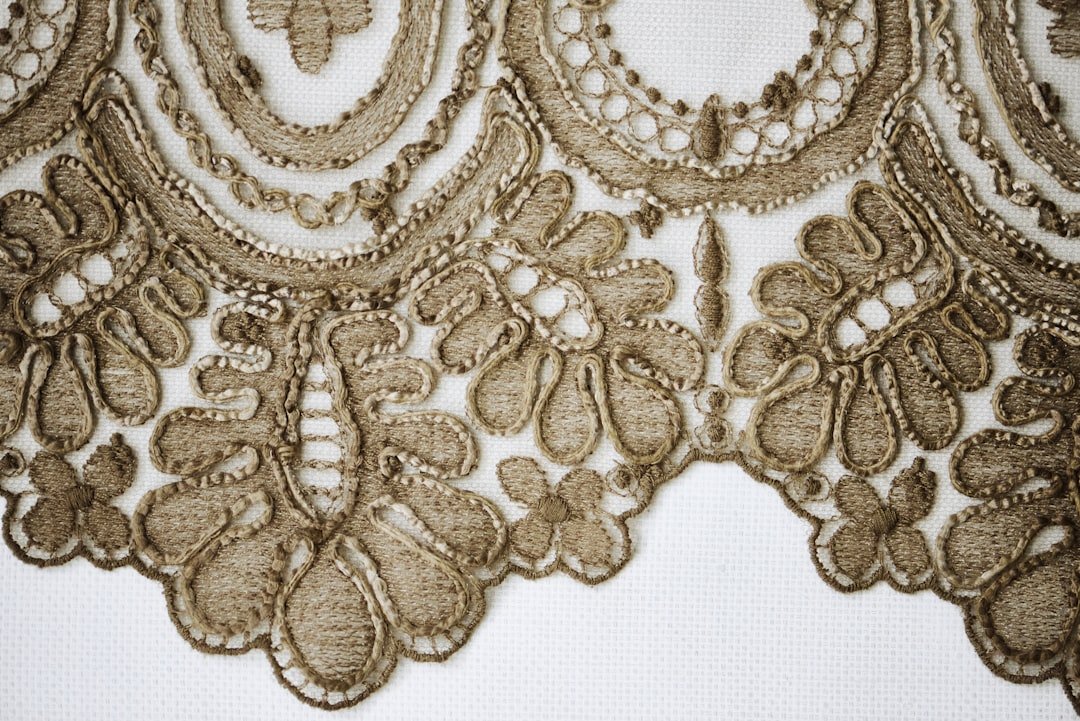 Close-up details of lace, beads, pearls, and threads used in fashion and tailoring. High-quality textile elements and handmade embellishments, showcasing the craftsmanship and elegance of garment design. Perfect for illustrating couture, sewing, fashion production, and artisanal clothing aesthetics.