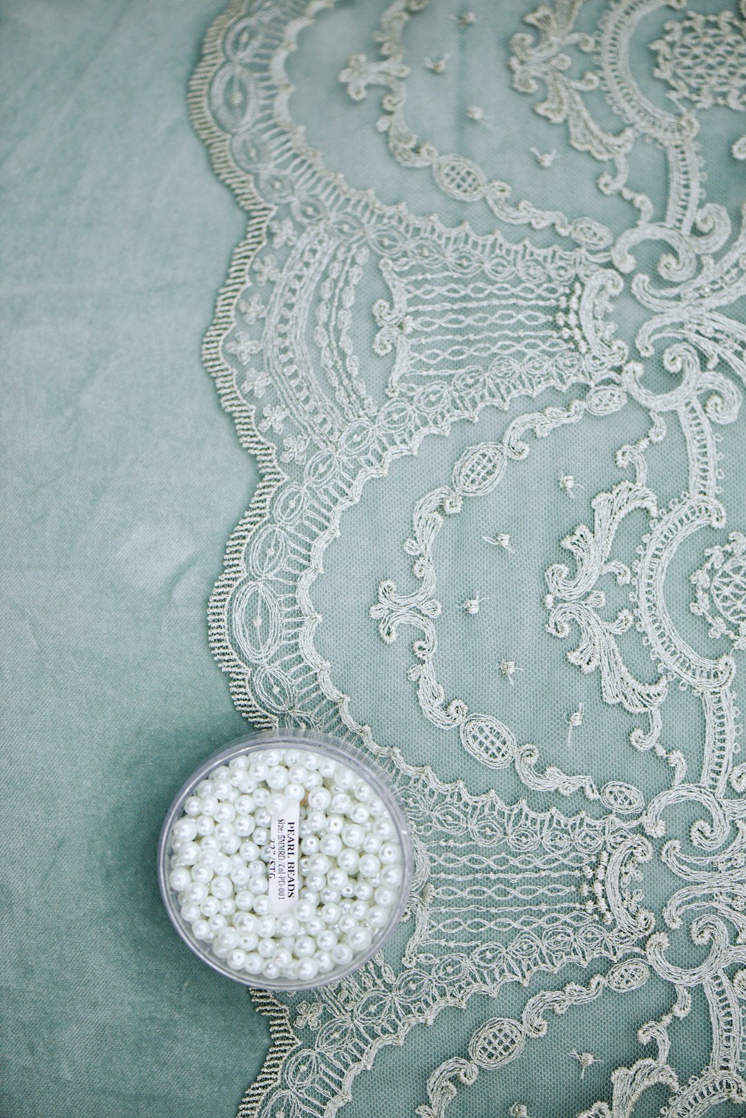 Close-up details of lace, beads, pearls, and threads used in fashion and tailoring. High-quality textile elements and handmade embellishments, showcasing the craftsmanship and elegance of garment design. Perfect for illustrating couture, sewing, fashion production, and artisanal clothing aesthetics.